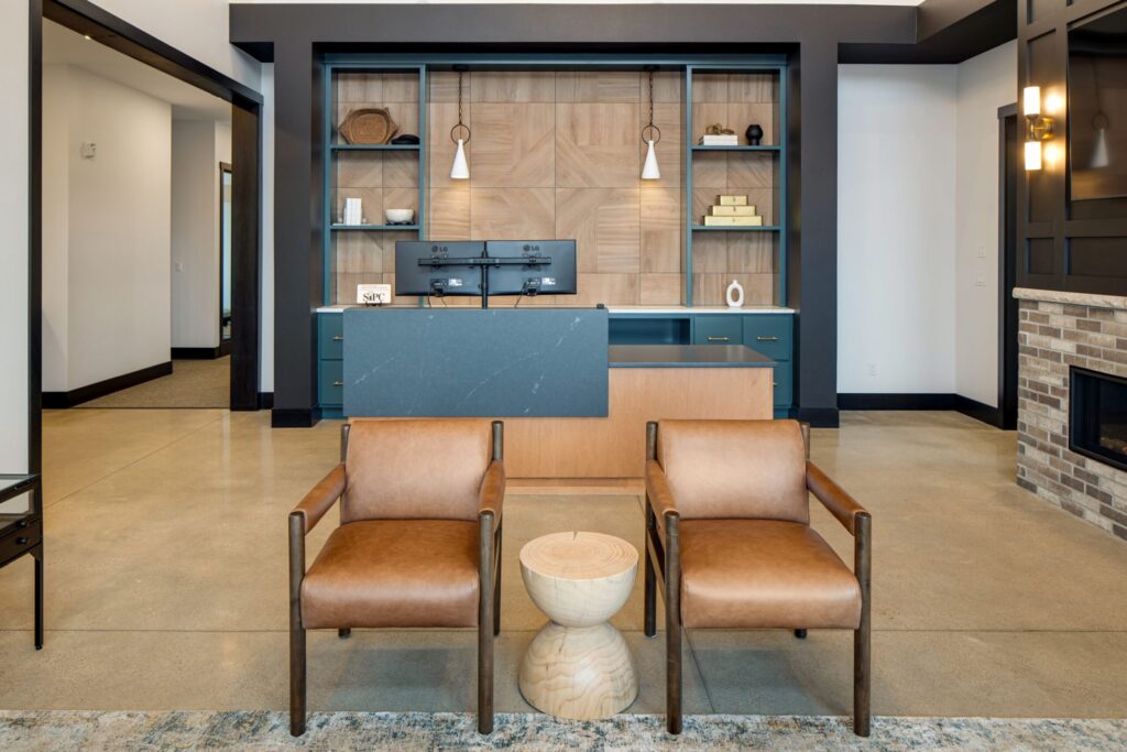 Modern office reception area with sleek desk, dual monitors, custom built-in shelving, and stylish pendant lighting.